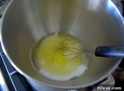 Egg whites, sugar, and cream of tartar in a bowl over a double boiler