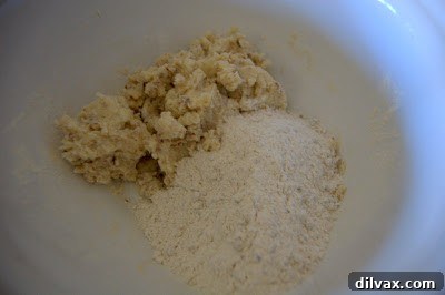Adding flour mixture to the butter and sugar, being combined by hand for shortbread dough