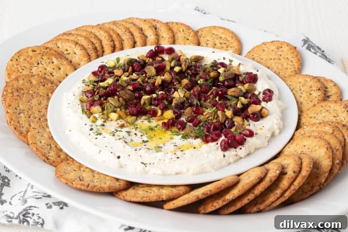 Vibrant whipped feta cheese dip topped with red pomegranate arils and green pistachios, ready to be served.