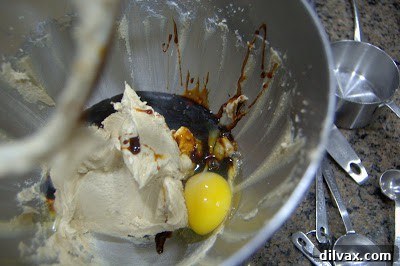 Wet ingredients including egg and molasses added to the creamed butter and sugar mixture in a mixer