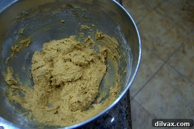 Flour mixture being gradually added to the wet ingredients in a stand mixer bowl