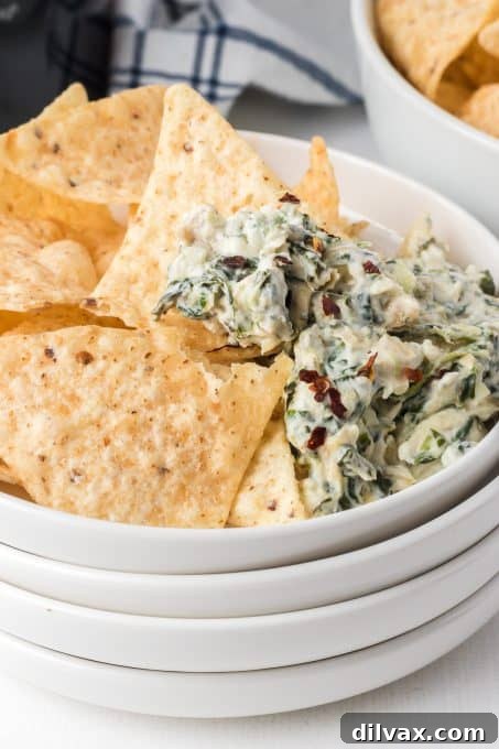 Warm & Cheesy Slow Cooker Spinach Artichoke Dip 3 Close-up of freshly made Crockpot Spinach Artichoke Dip in a slow cooker, showcasing its creamy texture and visible spinach and artichoke pieces.