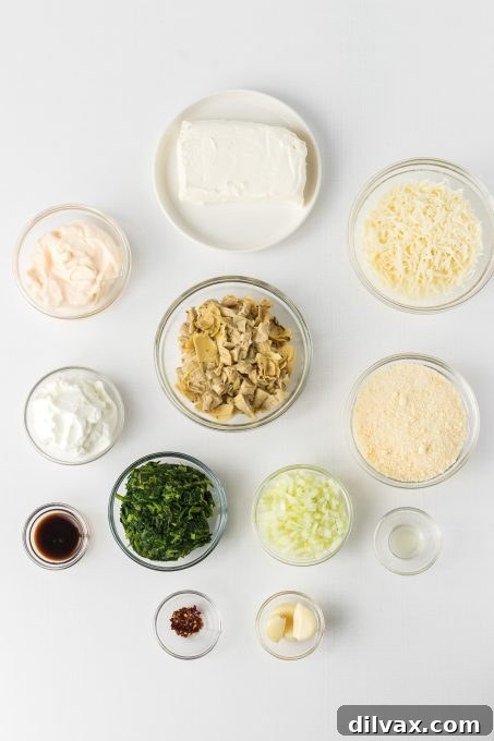 Warm & Cheesy Slow Cooker Spinach Artichoke Dip 4 A selection of fresh ingredients laid out on a kitchen counter, including canned artichoke hearts, frozen spinach, cream cheese, parmesan, mozzarella, mayonnaise, and Greek yogurt, for Crockpot Spinach Artichoke Dip.