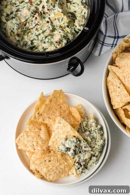 Warm & Cheesy Slow Cooker Spinach Artichoke Dip 9 A slow cooker brimming with a creamy, delectable spinach dip with artichokes, ready to be enjoyed.