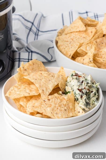 Warm & Cheesy Slow Cooker Spinach Artichoke Dip 10 A full crockpot of warm Crockpot Spinach Artichoke Dip, garnished with fresh herbs, ready for serving.