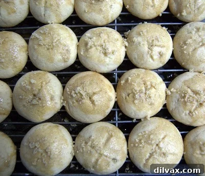 Brushing honey syrup on cookies and sprinkling with walnuts