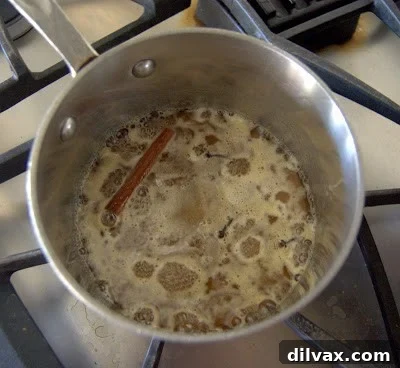 Honey syrup simmering in a saucepan with spices