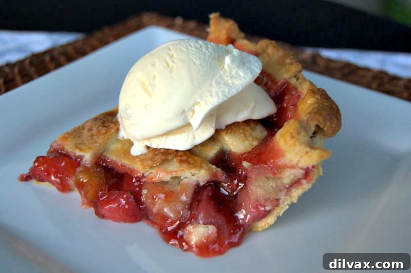 A slice of Lattice Strawberry Rhubarb Pie, revealing the rich, vibrant fruit filling and the flaky crust.