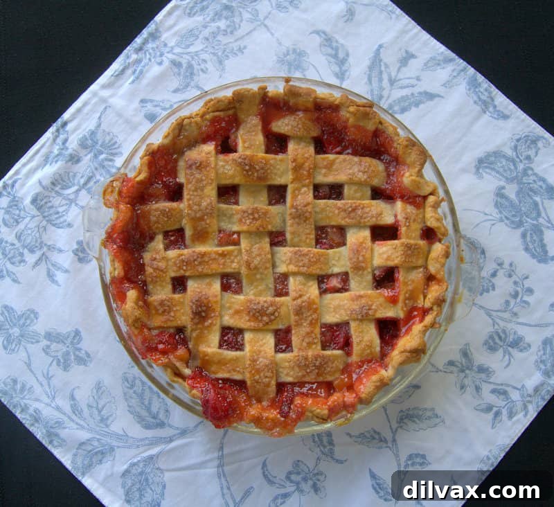 A full, vibrant Lattice Strawberry Rhubarb Pie, freshly baked and ready to be served, showcasing its impressive design.