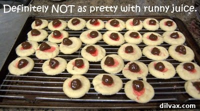 Freshly drizzled chocolate covered cherry thumbprint cookies on a cooling rack