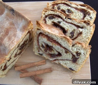 Freshly baked cinnamon raisin bread on a cutting board, ready to be sliced.