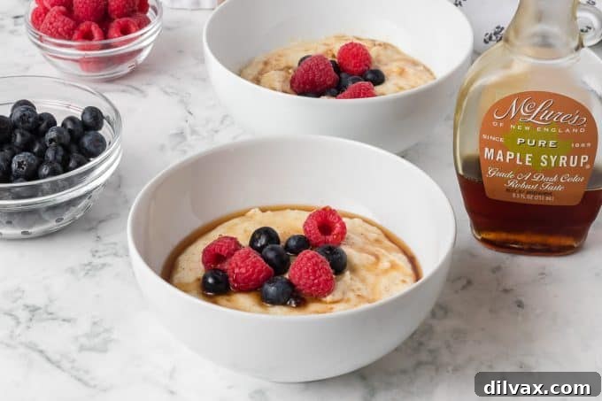 A beautifully prepared bowl of Cream of Wheat® topped with fresh blueberries and raspberries, a spoonful dipped in.