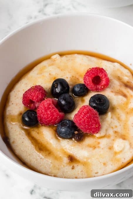 Overhead shot of a rustic wooden spoon scooping Cream of Wheat® from a bowl, garnished with berries.