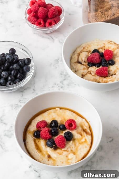 Two bowls of hot Cream of Wheat® porridge, richly topped with fresh berries, brown sugar, and maple syrup.