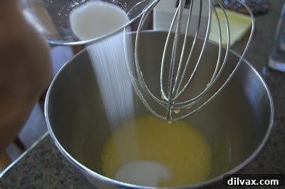 Sugar being added to beaten eggs and mixed until light and thoroughly blended.