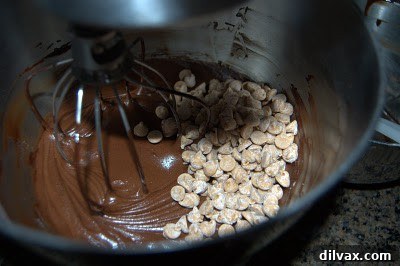 Peanut butter chips being stirred into the rich chocolate cookie dough.
