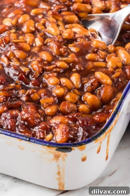 Sweet & Savory Bean Bake 10 A large serving of homemade baked beans in a white dish, garnished with fresh parsley.