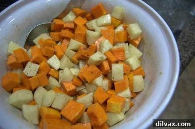 Butternut squash and potatoes expertly tossed with olive oil and a blend of seasonings in a bowl.