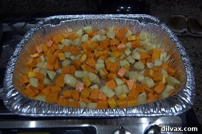 A spacious roasting pan generously filled with seasoned chicken, vibrant butternut squash, and cubed potatoes, ready for the oven.