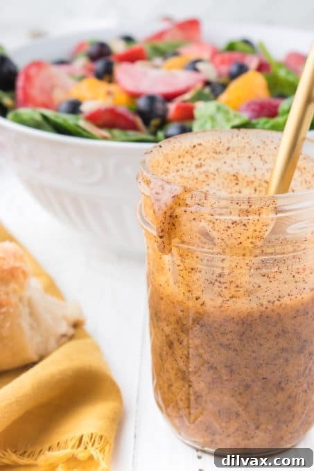 Creamy Poppy Seed Dressing 3 Close-up of poppy seed dressing with a spoon, highlighting its smooth texture and poppy seeds.