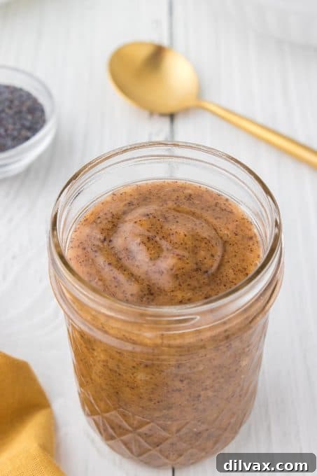 A close-up shot of a mason jar filled with bright, fresh Poppy Seed Salad Dressing, ready to be poured.