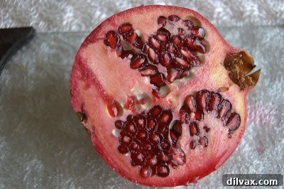 Pomegranate half submerged in water with seeds separating