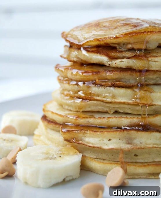 A close-up of pancake batter being poured onto a hot griddle, with some mashed banana visible, indicating the start of the cooking process for these delicious pancakes.