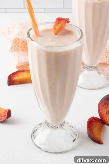 A peach lemonade shake in a glass with a straw