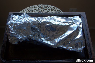 Sweet and Tangy Honey Mustard Ribs 3 Ribs wrapped securely in aluminum foil on a baking sheet, ready for the oven.