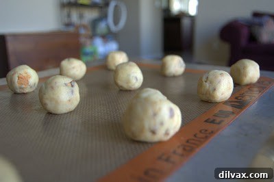 Rolled cookie dough balls on a baking sheet, ready for the oven, in a home setting.