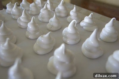 Pulling up the piping bag to form the peak of the meringue ghost.