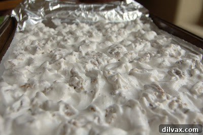 Daily Walnut Bake 21 Coated walnuts spread in a single layer on a foil-lined baking sheet.