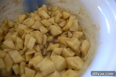 Apple pieces being tossed with the pie filling sauce