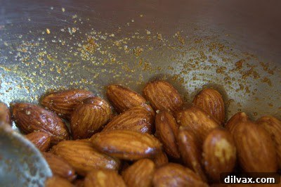 Spiced almonds spread on a parchment-lined baking sheet for final roasting.