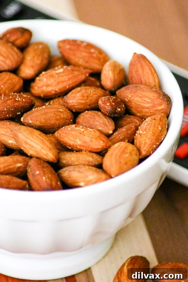 Close-up of a bowl filled with golden-brown Baked Spiced Almonds, highlighting their textured coating.
