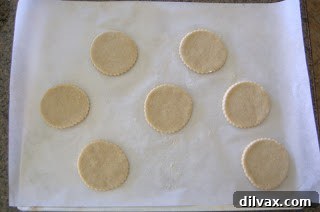Dough circles arranged on a parchment-lined baking sheet, awaiting the apple filling.