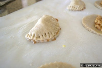Assembled apple hand pies, sealed with a fork along the edges, ready for egg wash and baking.
