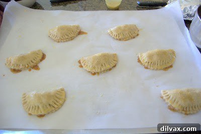 Apple hand pies brushed with egg wash and sprinkled with Turbinado sugar on a baking sheet.