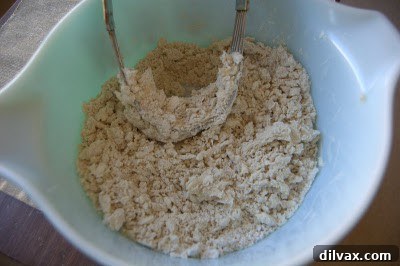 Pie crust mixture resembling coarse meal after fats have been cut into the flour, showing the ideal texture before adding water.