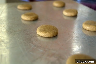 Decadent Spiced Cream Cookies 5 Unbaked spice cookie dough balls flattened on a baking sheet, ready for the oven