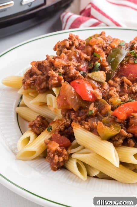 A rich meat sauce with colorful peppers and onions served over pasta.