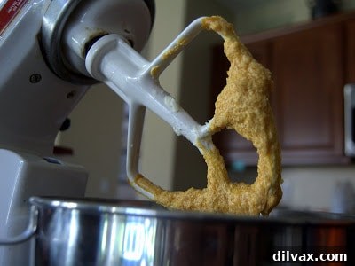 Mixing pumpkin puree and vanilla into creamed butter and sugar for cookie dough.