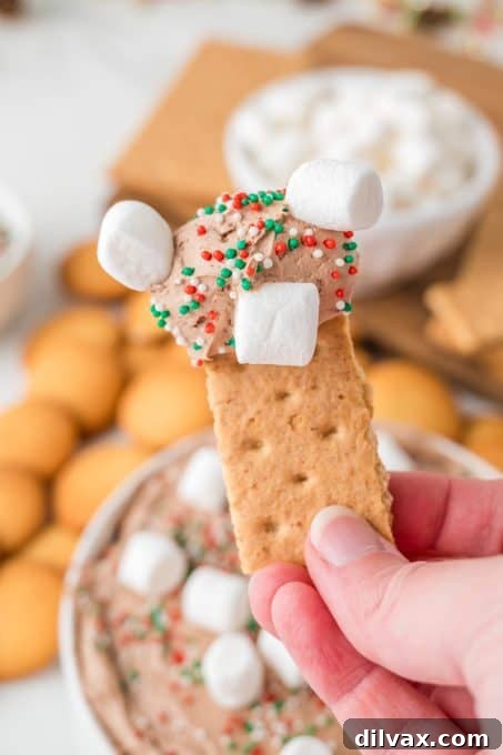 A spoonful of Hot Cocoa Dip, showing its creamy texture and marshmallows, ready to be eaten.