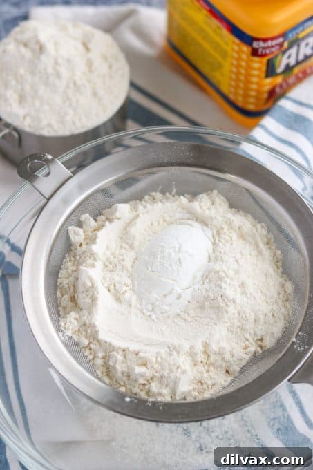 All-purpose flour and cornstarch measured in a fine mesh sieve, ready for thorough sifting to create cake flour.