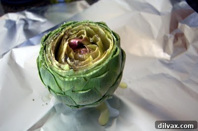 An artichoke seasoned with herbs and olive oil, ready to be wrapped in foil.