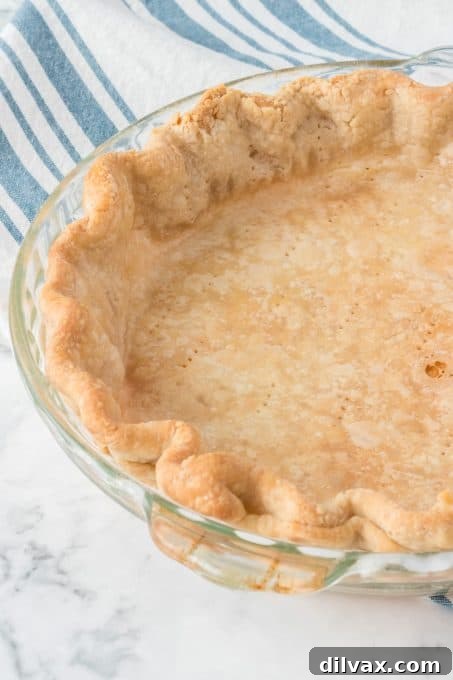 A baker skillfully rolling out homemade pie crust dough on a lightly floured surface with a wooden rolling pin.