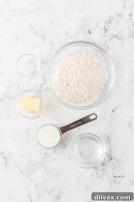 Essential ingredients laid out for making homemade pie crust: flour, salt, shortening, butter, and a glass of ice water.