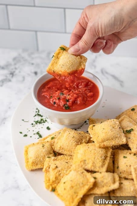 Dipping breaded ravioli into marinara.