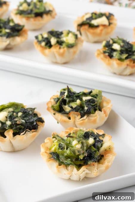 A small stack of mini spinach phyllo bites on a white plate, highlighting their individual serving size.