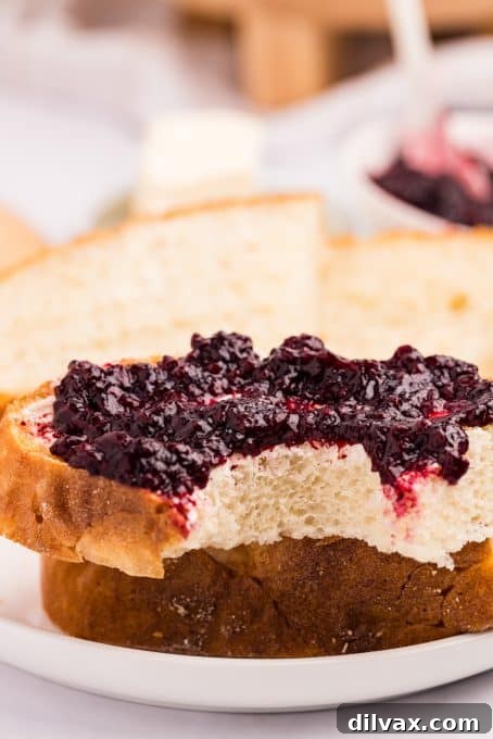 A slice of freshly baked Dutch Oven Bread topped with a generous dollop of fruit jelly.